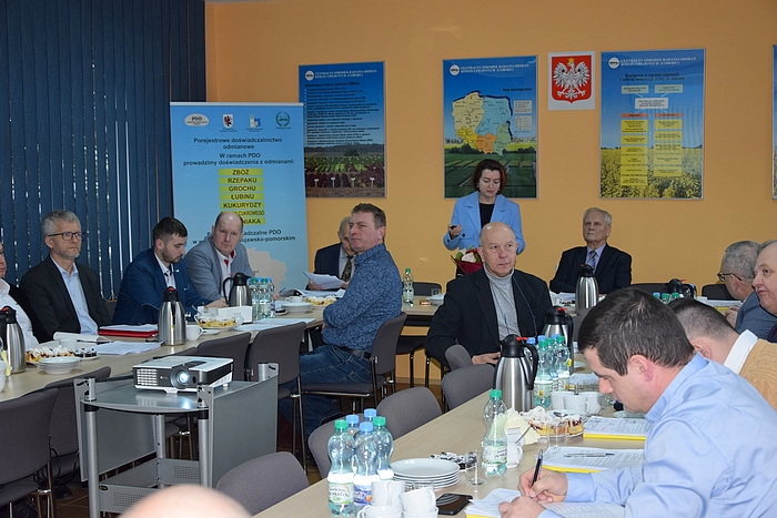 Stojąca dyrektor SDOO w Chrząstowie, ubrana w niebieski żakiet, referuje sprawozdanie przed siedzącymi przy stole członkami KPZ PDO.