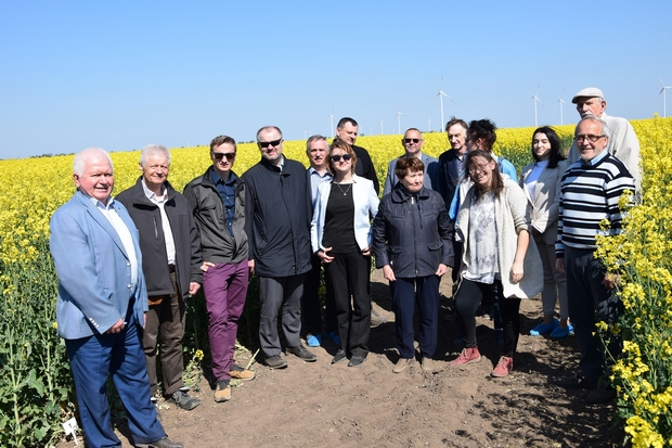 zdjęcie grupowe wszystkich uczestników spotkania na tle kwitnącego na żółto rzepaku ozimego