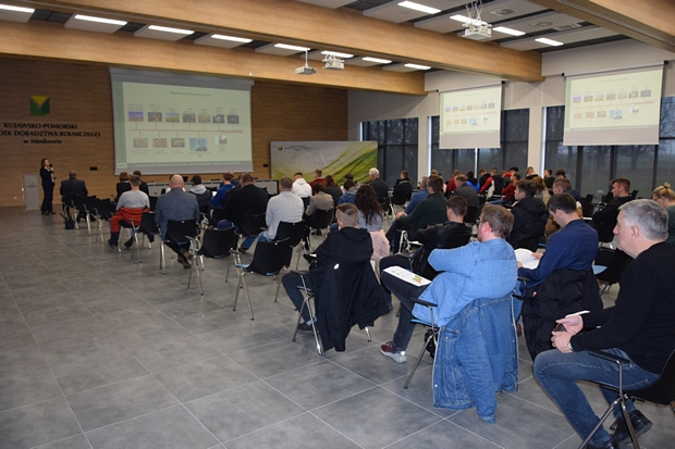 siedzący na krzesłach uczestnicy szkolenia, na dalszym planie ekran z prezentacją