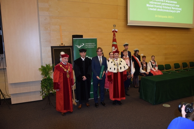 Daniel Krauklis w towarzystwie promotora, Dziekana i Prodziekana UP w Poznaniu na tle loga uczelni