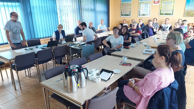 uczestnicy szkolenia siedzący przy stołach na sali wykładowej