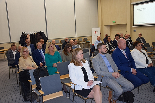 Członkowie Zespołu siedzący na krzesłach na sali wykładowej