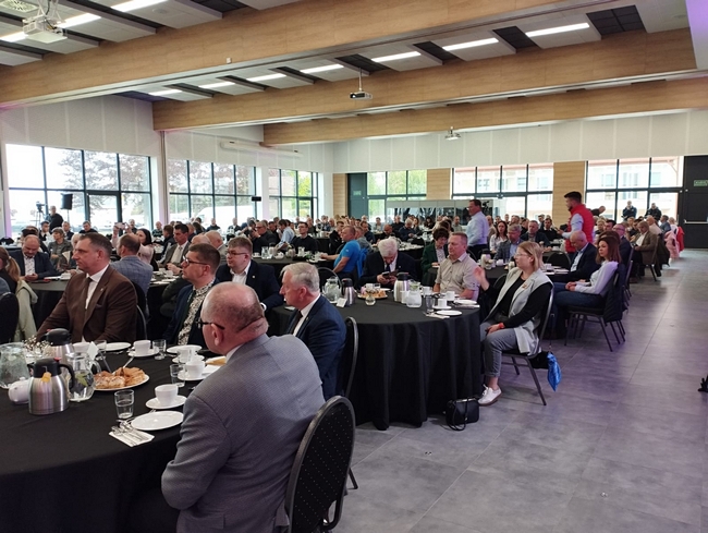 zaproszeni goście siedzący przy stołach na sali konferencyjnej