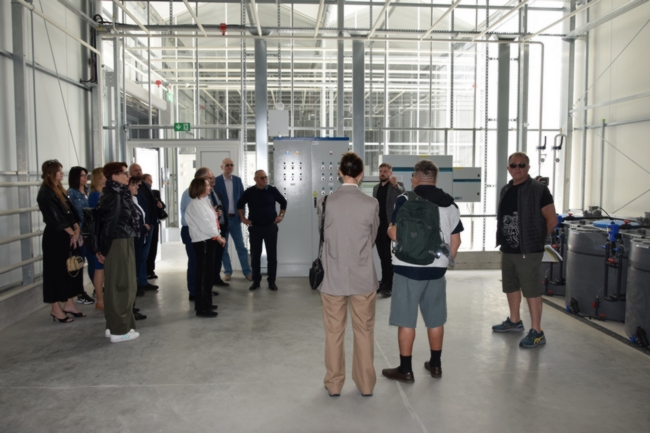 uczestnicy spotkania stojący w szklarni przed komputerem sterującym