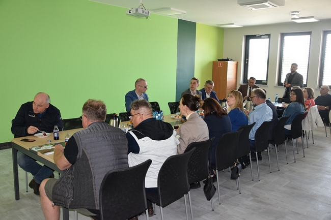 uczestnicy spotkania siedzący na stole na sali konferencyjnej  