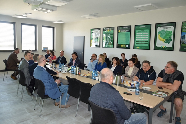 uczestnicy spotkania siedzący na stole na sali konferencyjnej  