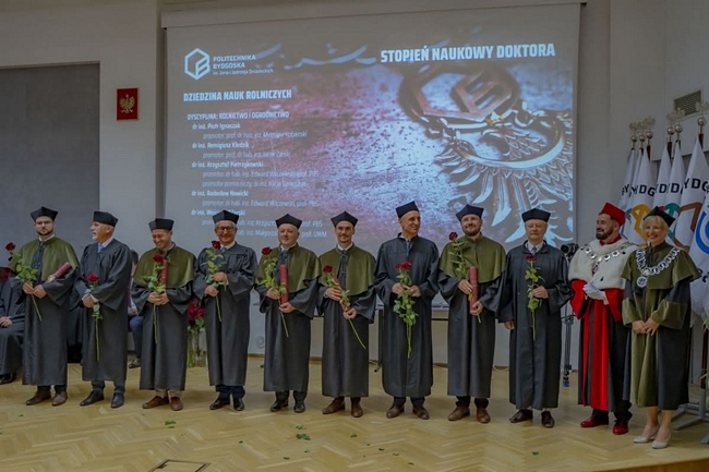 doktoranci i władze uczelni stojący na scenie 