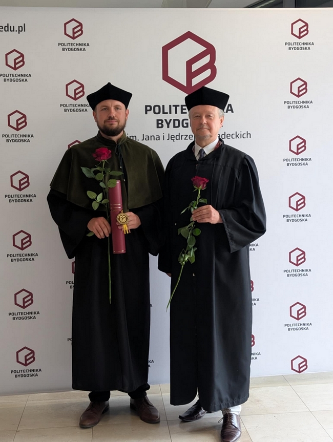 Wojciech Pilarski i dr hab. inż. Krzysztof Gęsiński stojący na tle loga Politechniki Bydgoskiej