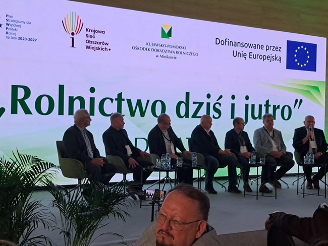 członkowie debaty siedzący na scenie